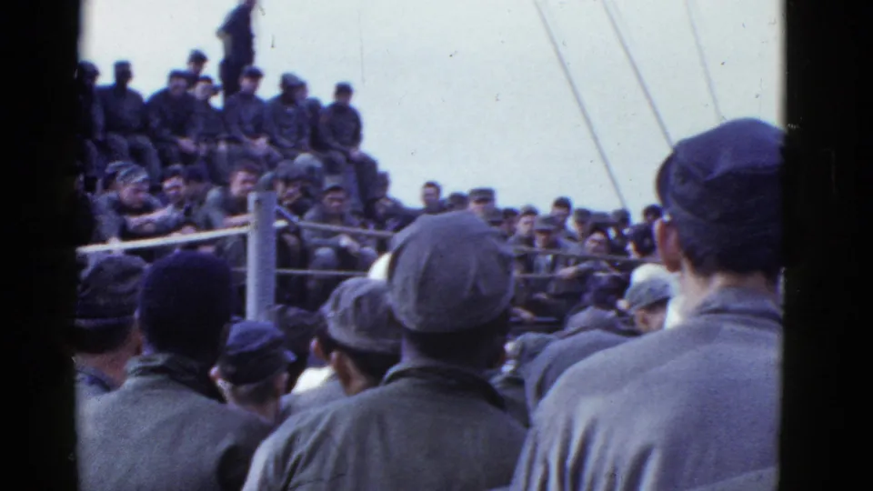 Uniformed men sit and stand around a shipboard boxing ring in this 1950s San Francisco-area home-movie frame.