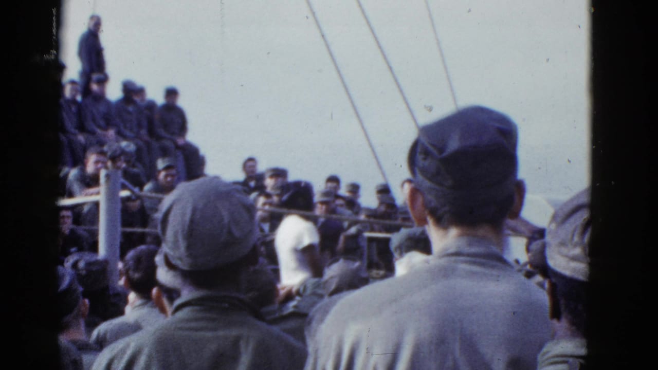 1950s San Francisco 8mm frame showing men in caps and uniform-like clothing crowded on a ship deck under an overcast sky.