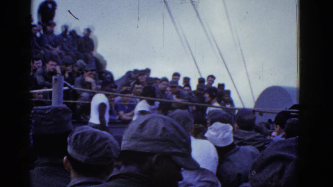 Dense group of spectators seated and standing on a vessel deck.
