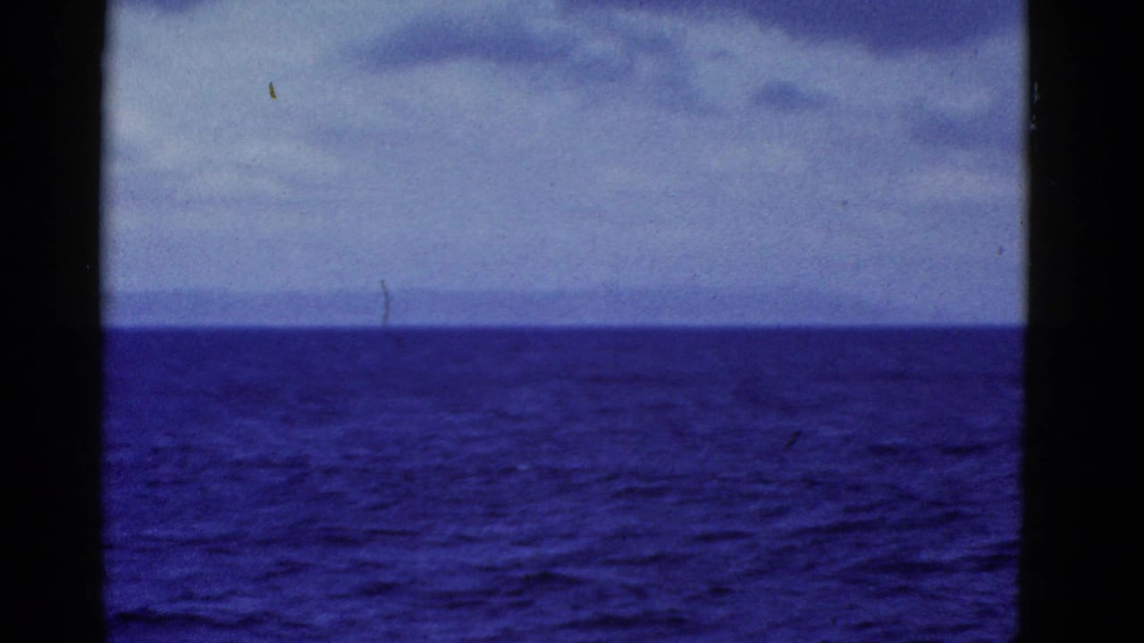 1952 8mm home-movie frame showing blue ocean, distant land, and cloudy sky from a vessel near San Francisco.