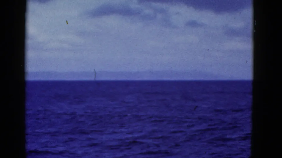 1952 8mm home-movie frame showing blue ocean, distant land, and cloudy sky from a vessel near San Francisco.