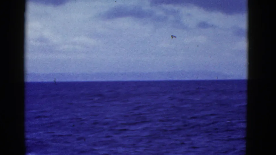 Blue ocean and a faint distant shoreline appear beneath cloud cover in this 1952 San Francisco-area 8mm frame.