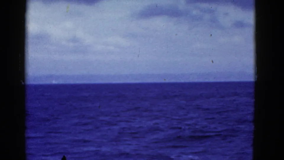 A vessel-side 8mm view shows choppy blue water, distant land, and overcast sky near San Francisco in 1952.