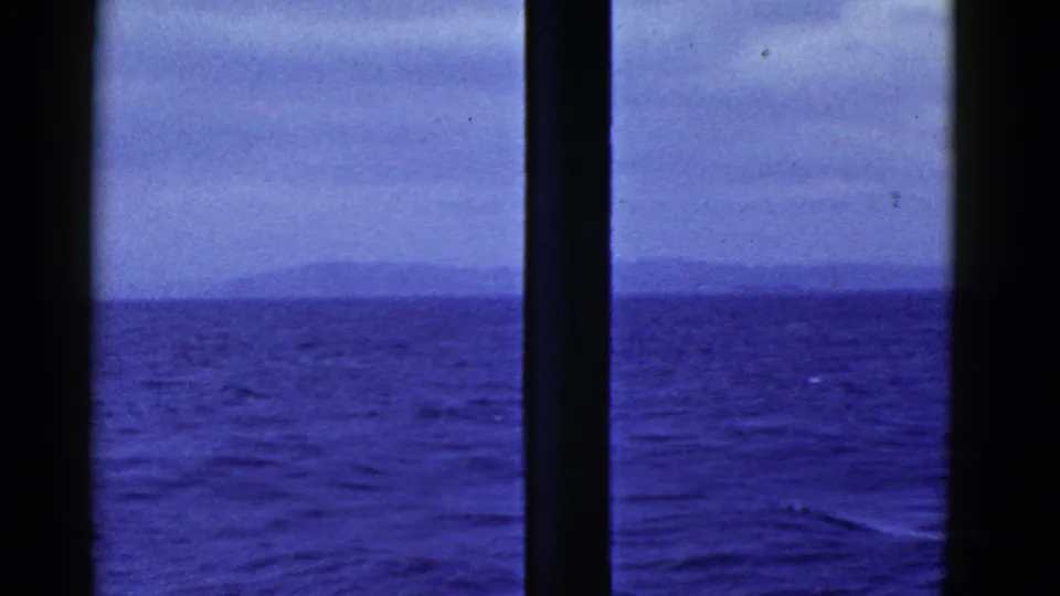 Ship-window view of blue water, low waves, and a hazy landmass, consistent with the clip's 1952 San Francisco metadata.