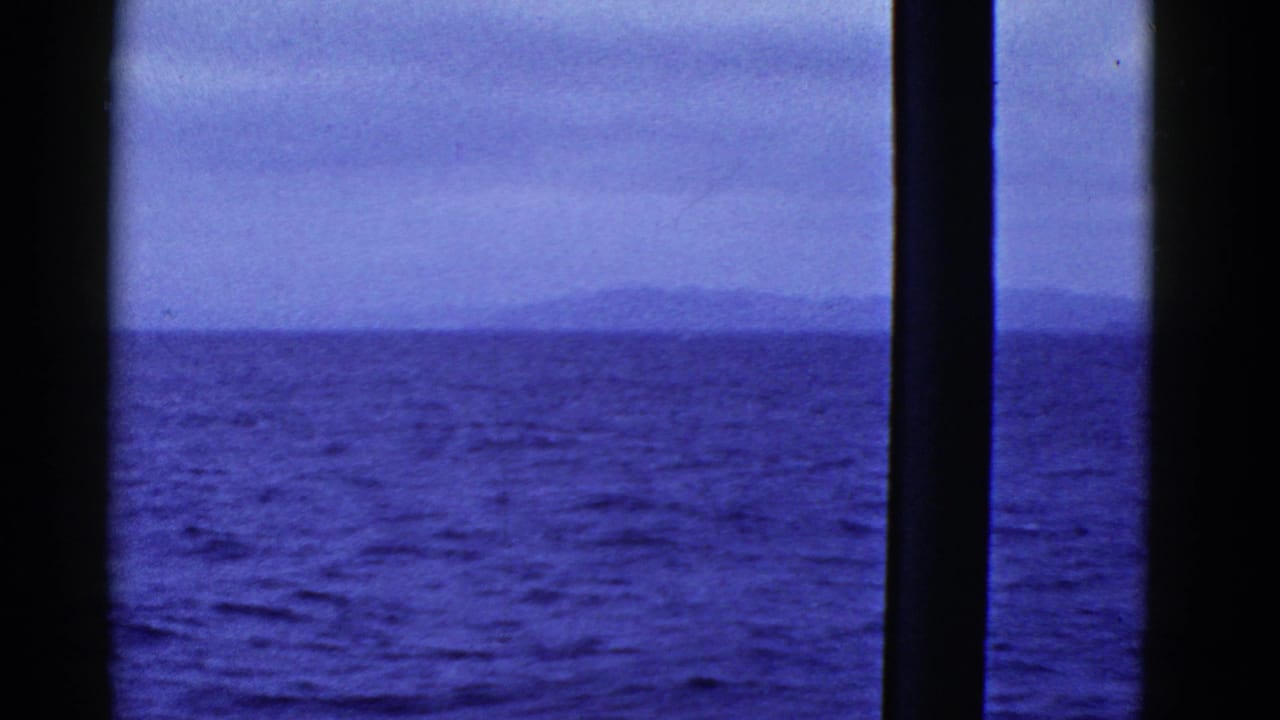 1950s 8mm home-movie view near San Francisco showing choppy bay water, an overcast sky, and distant land through a boat window.