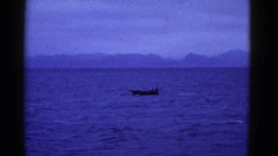 A small boat appears against deep blue water and a soft, mountainous horizon in this 1952 San Francisco home-movie frame.