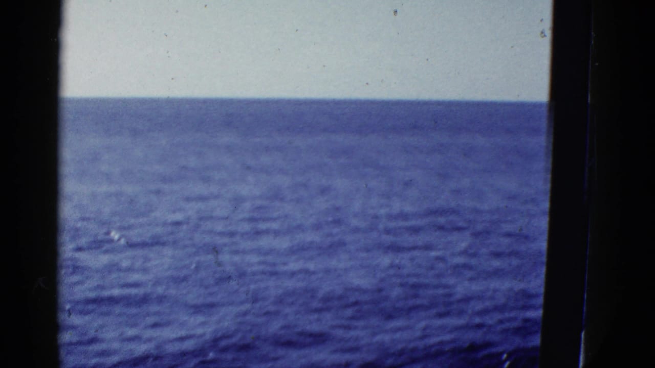 Blue water and horizon framed by dark vertical edges from a vessel.
