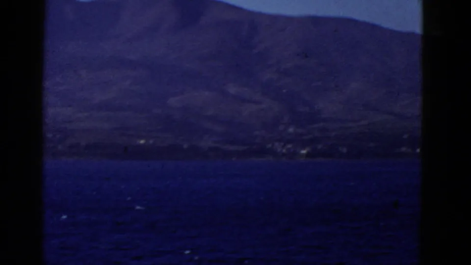 Distant coastal land and low mountains appear beyond blue water, likely from the San Francisco-area travel sequence.