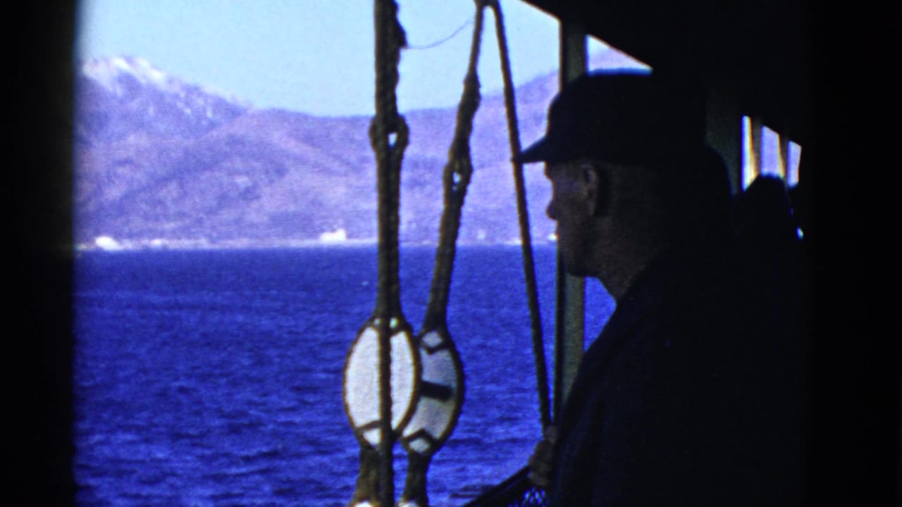In 1952 San Francisco-area home-movie footage, a man in a dark cap stands in silhouette beside rigging with water and mountains beyond.