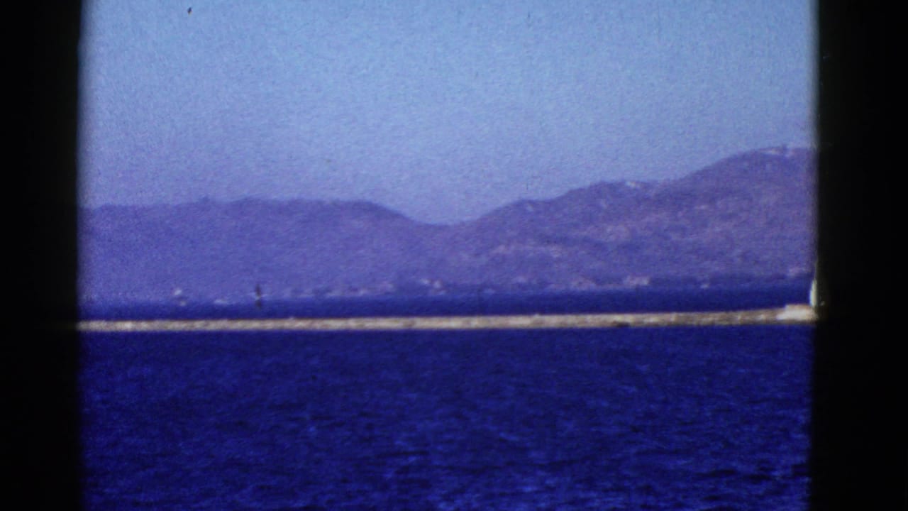 San Francisco Bay water and distant hills appear beyond a long pier, framed by dark vertical edges from the vessel.