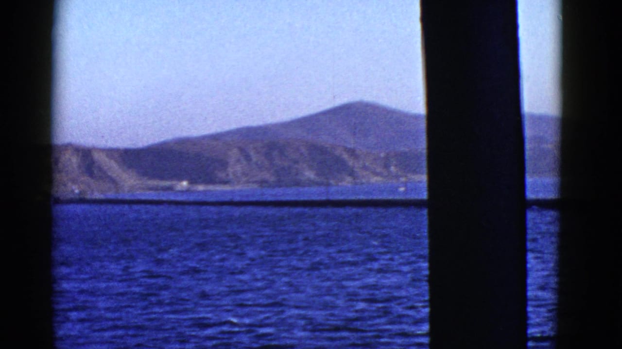 Distant mountain ridge across blue water under a clear sky.