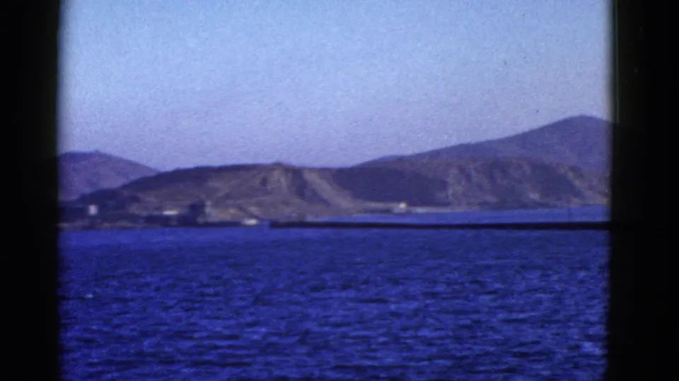 San Francisco-area bay landscape on 8mm film, with distant hills and water seen through dark structural bars.