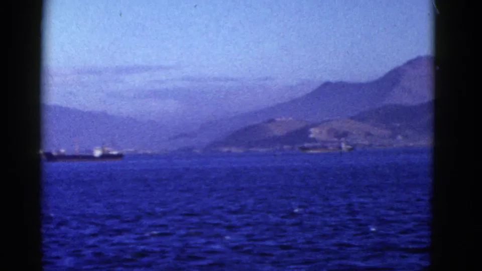 1950s San Francisco-area boat view with a small vessel on blue water and distant hills along the shoreline.