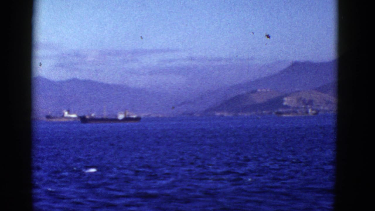 Early 1950s San Francisco Bay home-movie frame showing cargo ships offshore, hazy hills, blue water, and dark frame edges.