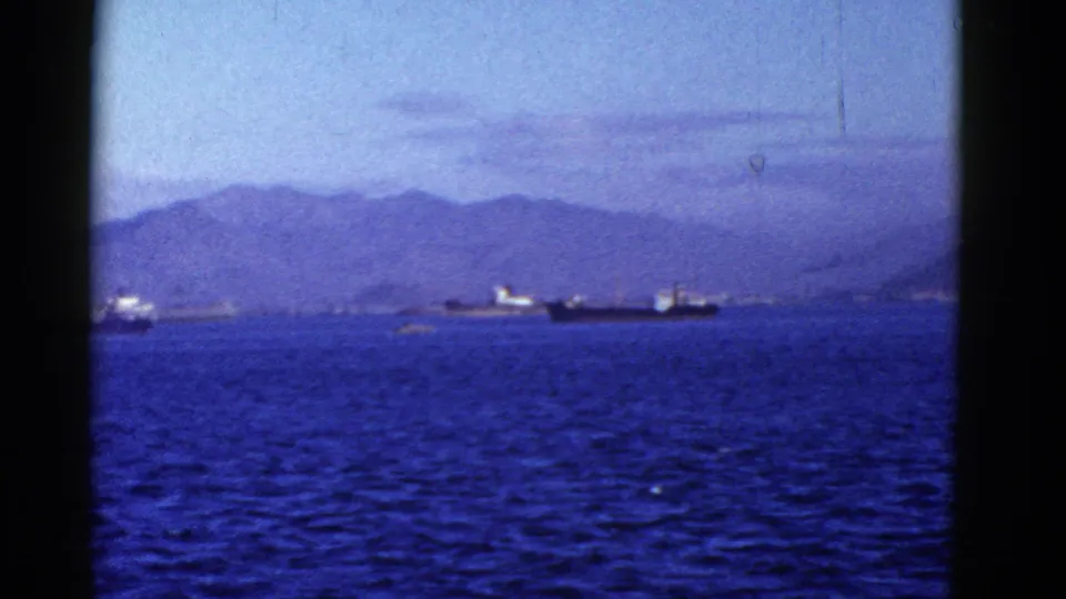 Early 1950s San Francisco Bay frame with cargo vessels, rippled water, distant hills, and a soft home-movie look.
