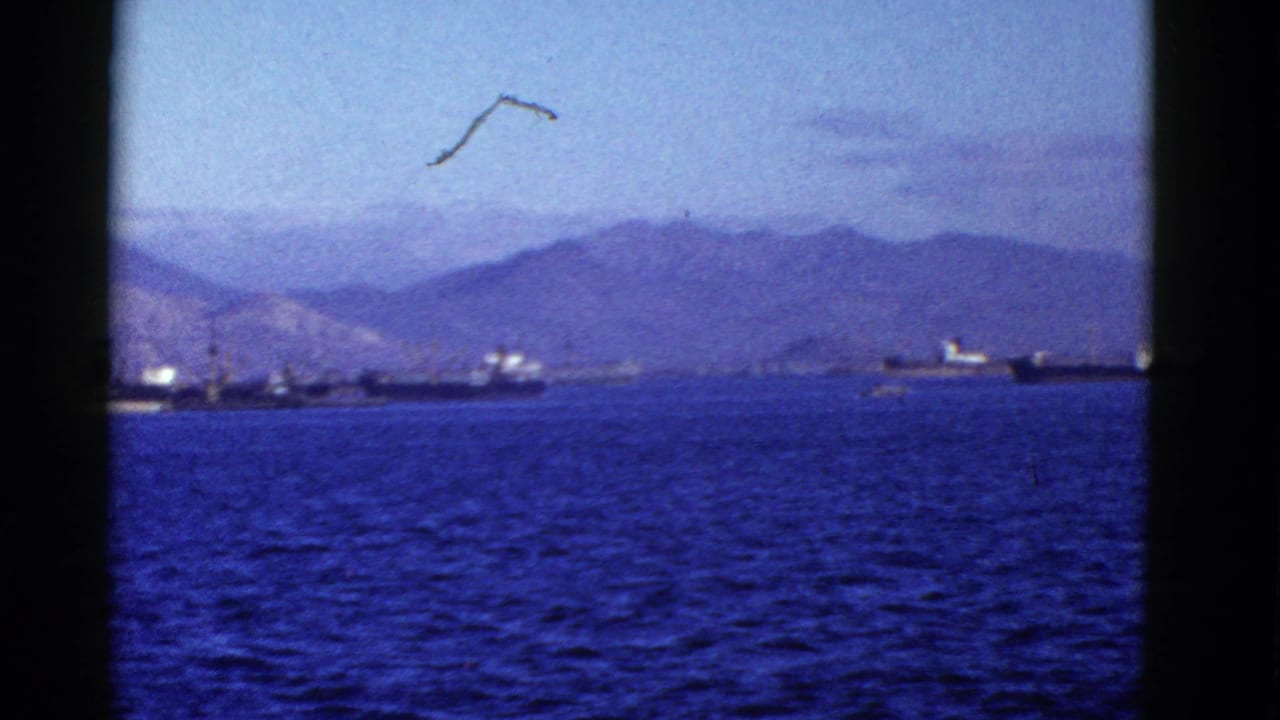 Early 1950s San Francisco Bay view with blue water, distant ships, hazy mountains, and dark window-like edges.