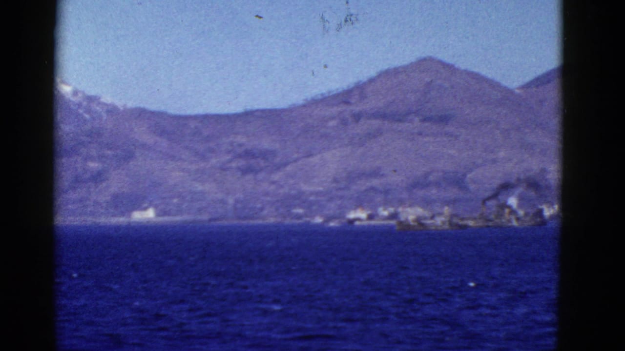 1952 San Francisco-area 8mm view from the water toward mountains, shoreline structures, small vessels, and smoke near the coast.