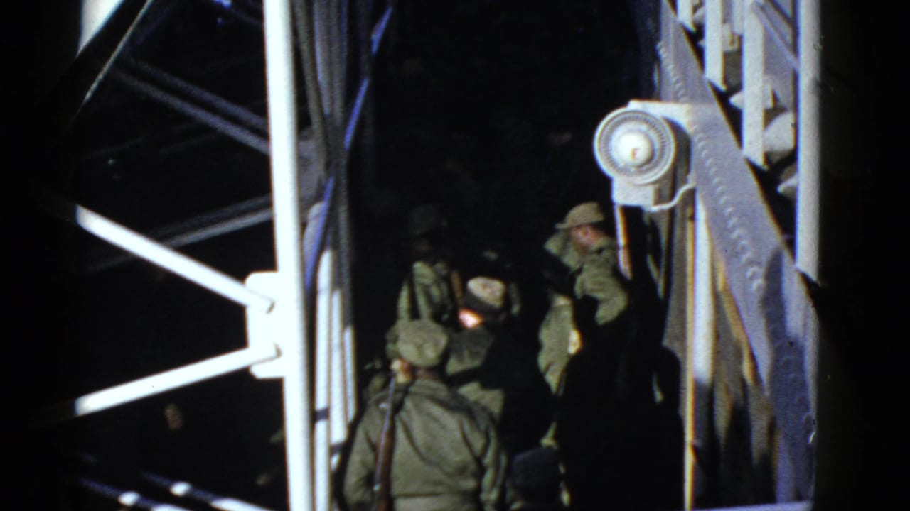 Early 1950s San Francisco home-movie frame showing uniformed soldiers clustered under railings and beams at night.