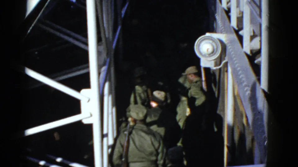 Early 1950s San Francisco home-movie frame showing uniformed soldiers clustered under railings and beams at night.