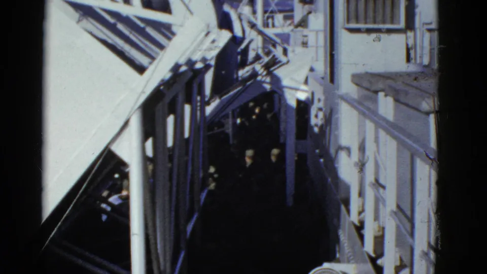1952 San Francisco shipboard view with uniformed people in a narrow passage, framed by white railings and structural beams.