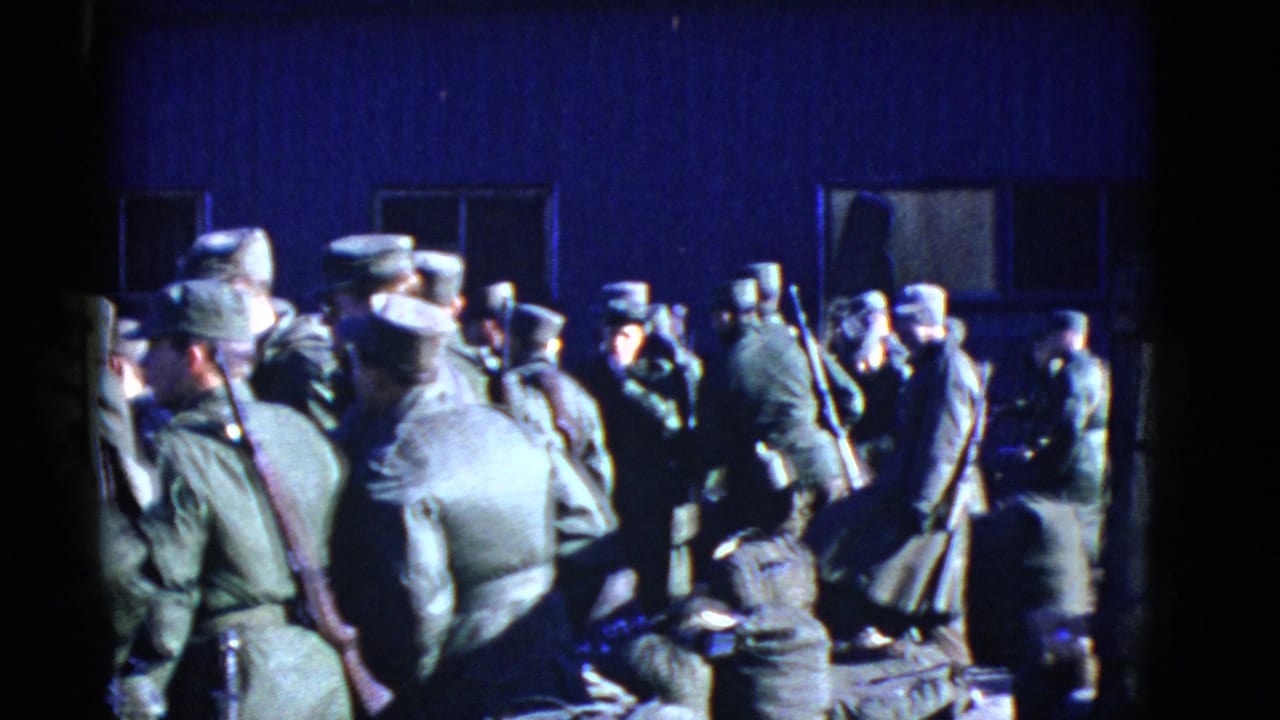 1952 San Francisco 8mm frame showing U.S. Army soldiers in olive uniforms gathered outdoors by a dark building.