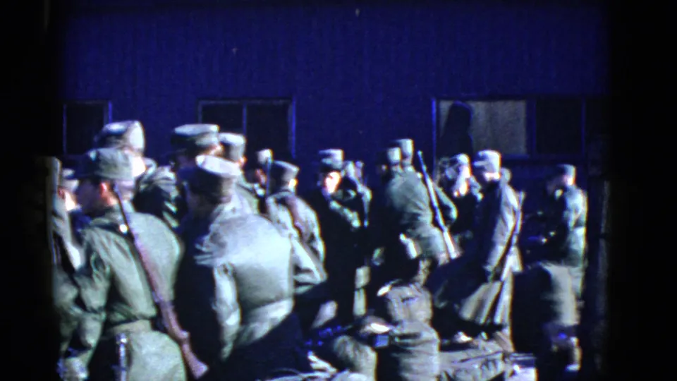 1952 San Francisco 8mm frame showing U.S. Army soldiers in olive uniforms gathered outdoors by a dark building.