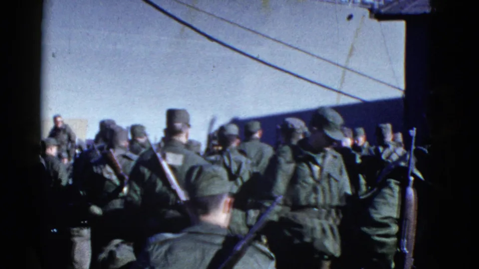 Handheld 8mm frame of troops seen from behind as they gather near a ship at the San Francisco waterfront.
