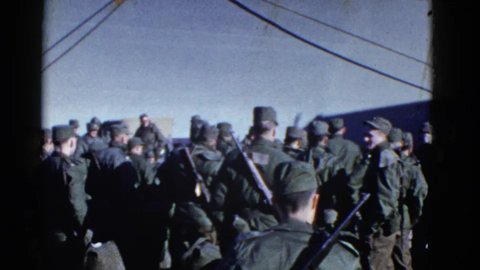 1952 San Francisco home-movie frame showing uniformed men waiting near a ship, with rigging lines overhead.