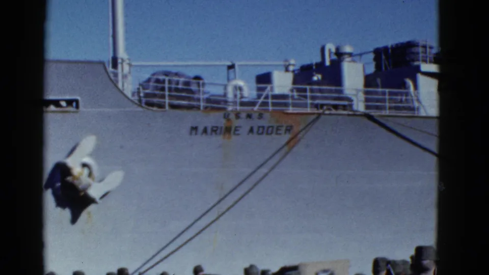 1952 San Francisco footage frames the Marine Adder hull and anchor above uniformed men standing on the pier below.