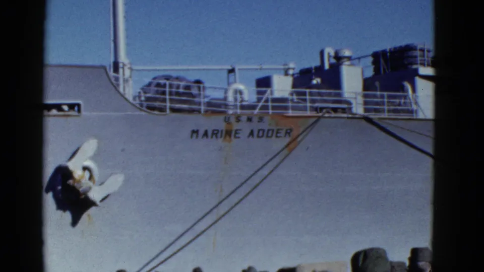 1952 San Francisco pier-side frame of the U.S.N.S. Marine Adder, with hull lettering, anchor, rigging, and uniformed personnel below.