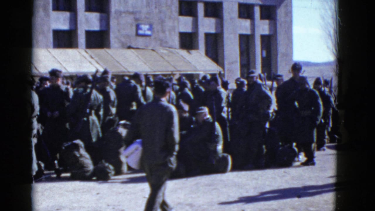 A passerby crosses in front of uniformed men waiting with bags outside a San Francisco building in early-1950s home-movie footage.