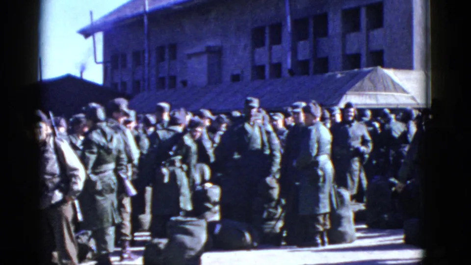 Uniformed soldiers gather with duffel bags outside an institutional building in the San Francisco military setting.