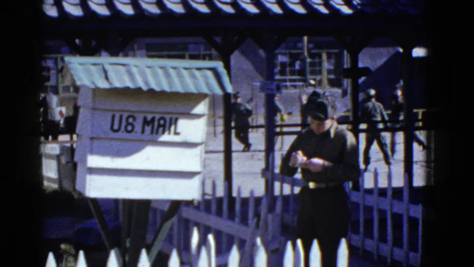 A U.S. Mail box, fence, nearby soldiers, and a woman in dark clothing appear in the supported San Francisco home-movie frame.