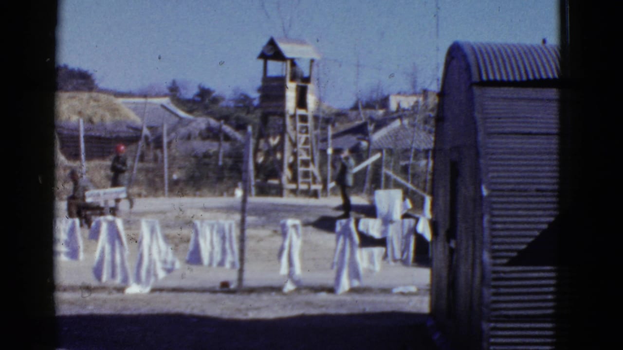1952 San Francisco military grounds with white laundry drying, a wooden watchtower, fencing, and barracks-style buildings.