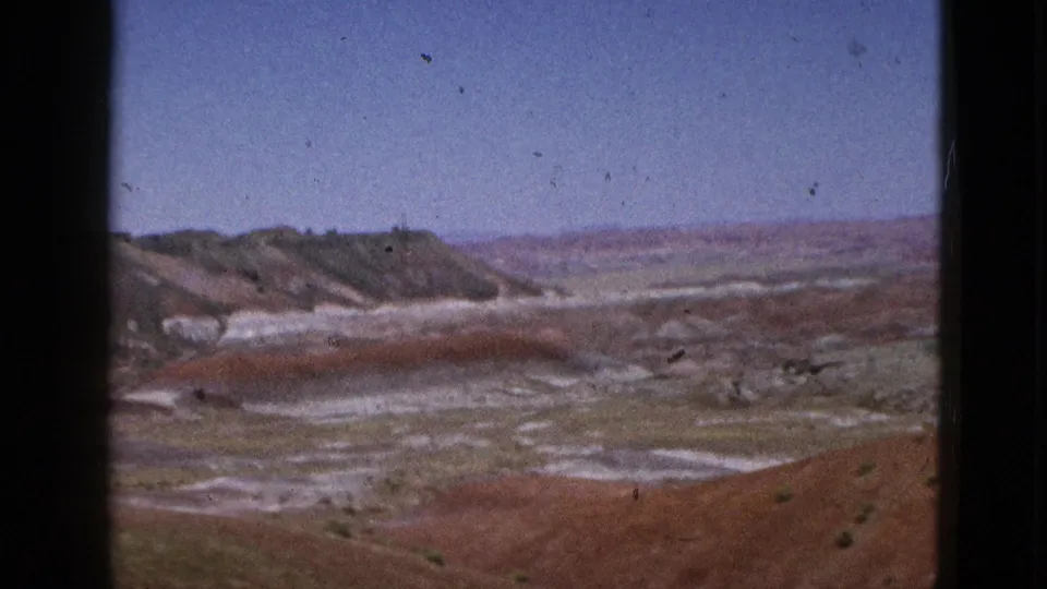Panoramic 8mm frame of California desert terrain, showing red foreground slopes, pale mineral flats, distant ridges, and a clear sky.