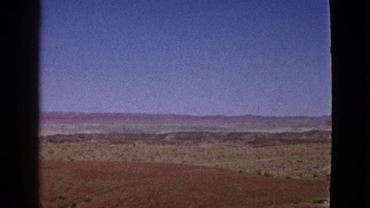 Arid hillside and distant ridgeline beneath a broad blue sky.