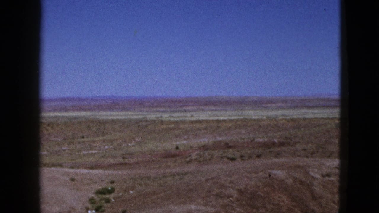 Dry open field below a blue sky, framed by dark vertical edges.