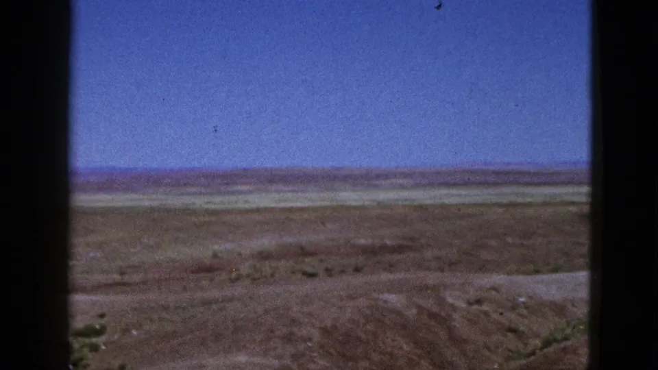 1953 California home-movie view of a broad dry plain, low vegetation, and a pale horizon under a clear blue sky.
