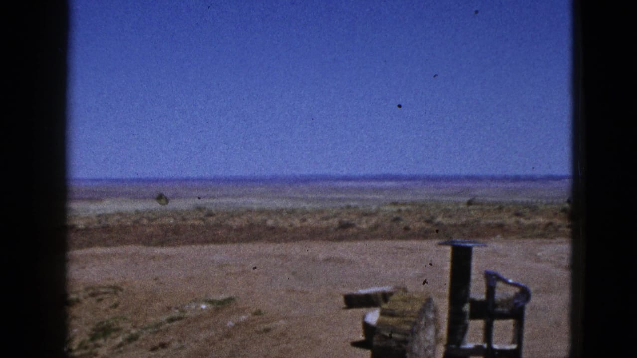 1953 California desert view with graded earth, open horizon, and a wooden post or spool beside a metal chair-like frame.
