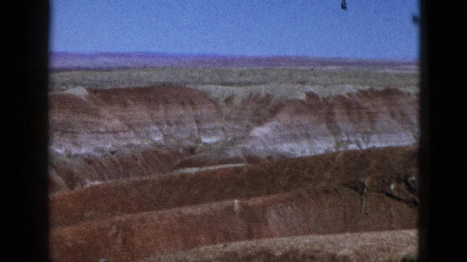 1953 California 8mm frame showing layered red and white canyon formations from a distant overlook.