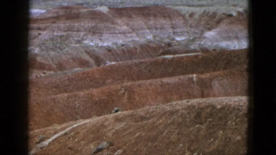 1953 California 8mm frame showing a rounded foreground ridge before layered red and white canyon walls.