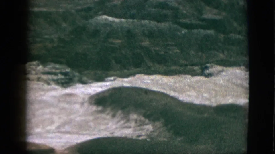 1953 California 8mm frame showing a high vantage view over rolling hills, pale slopes, and soft grain.