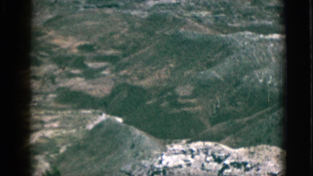 Soft aerial view over rugged plateau terrain with dark film borders.