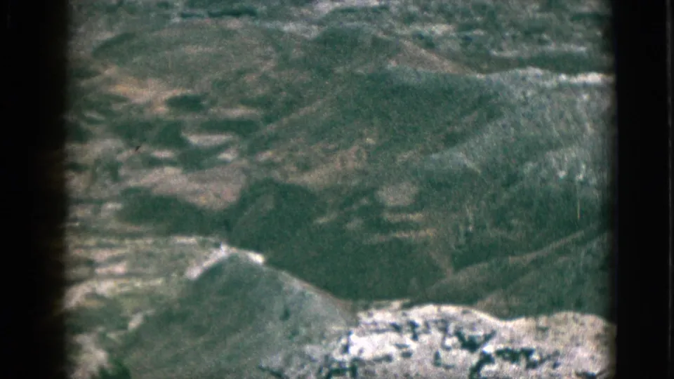 1953 8mm California footage appears to show a hazy aerial or elevated view across rugged plateau hills and pale rocky ground.