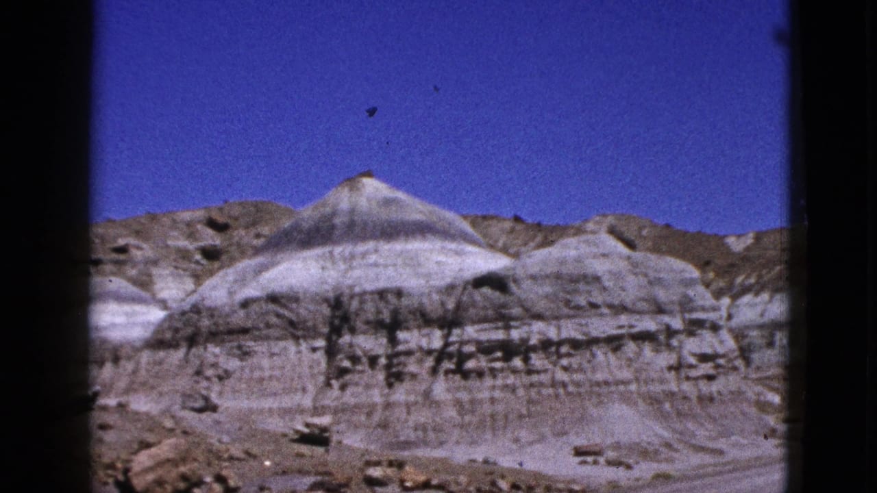 Layered pale rock formation below a deep blue sky in desert terrain.