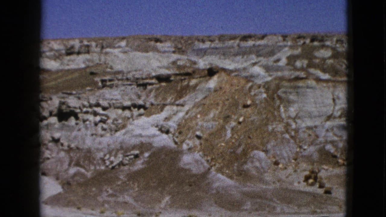 Eroded desert mound and layered rock shelves beneath a blue sky.