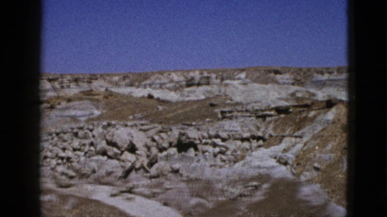1953 California 8mm frame showing pale canyon rock, boulder fields, dry slopes, and clear blue sky.