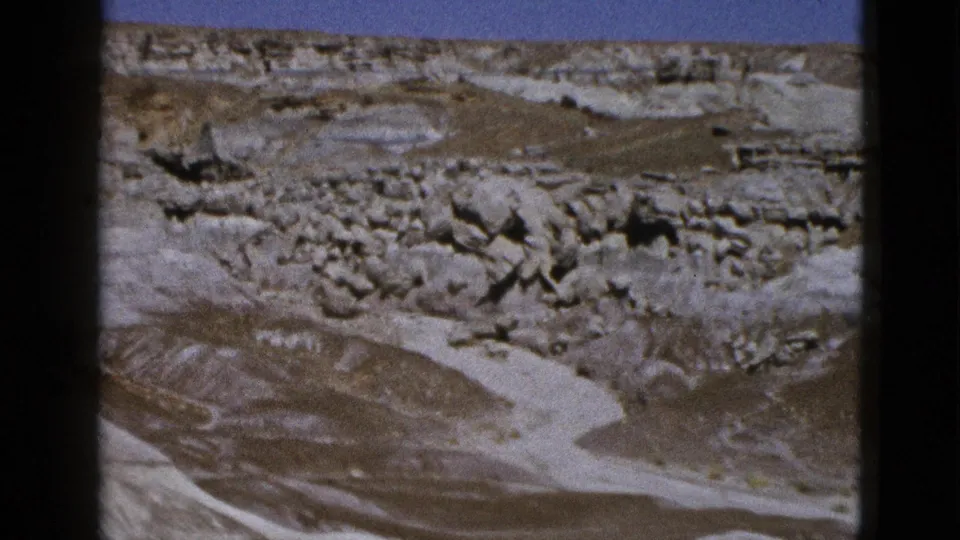 1953 Arizona desert view with pale eroded formations, rocky outcrops, sparse vegetation, and handheld 8mm framing.
