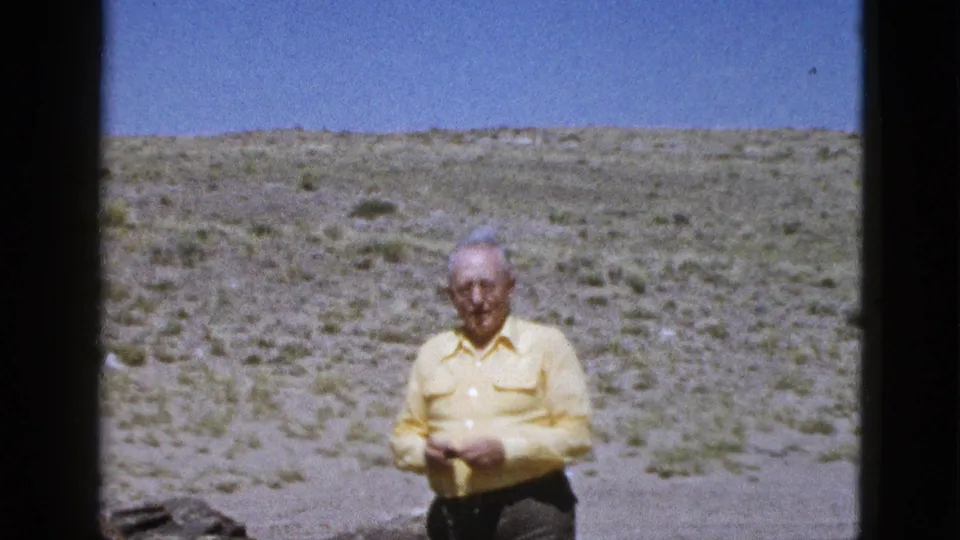 In this 1953 Arizona home-movie frame, the man appears to adjust his hands or clothing while standing in open scrubland.