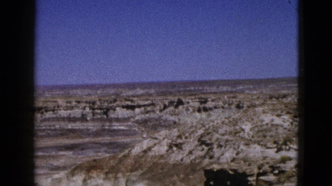 Wide desert view with layered rock ridges beneath a clear blue sky.